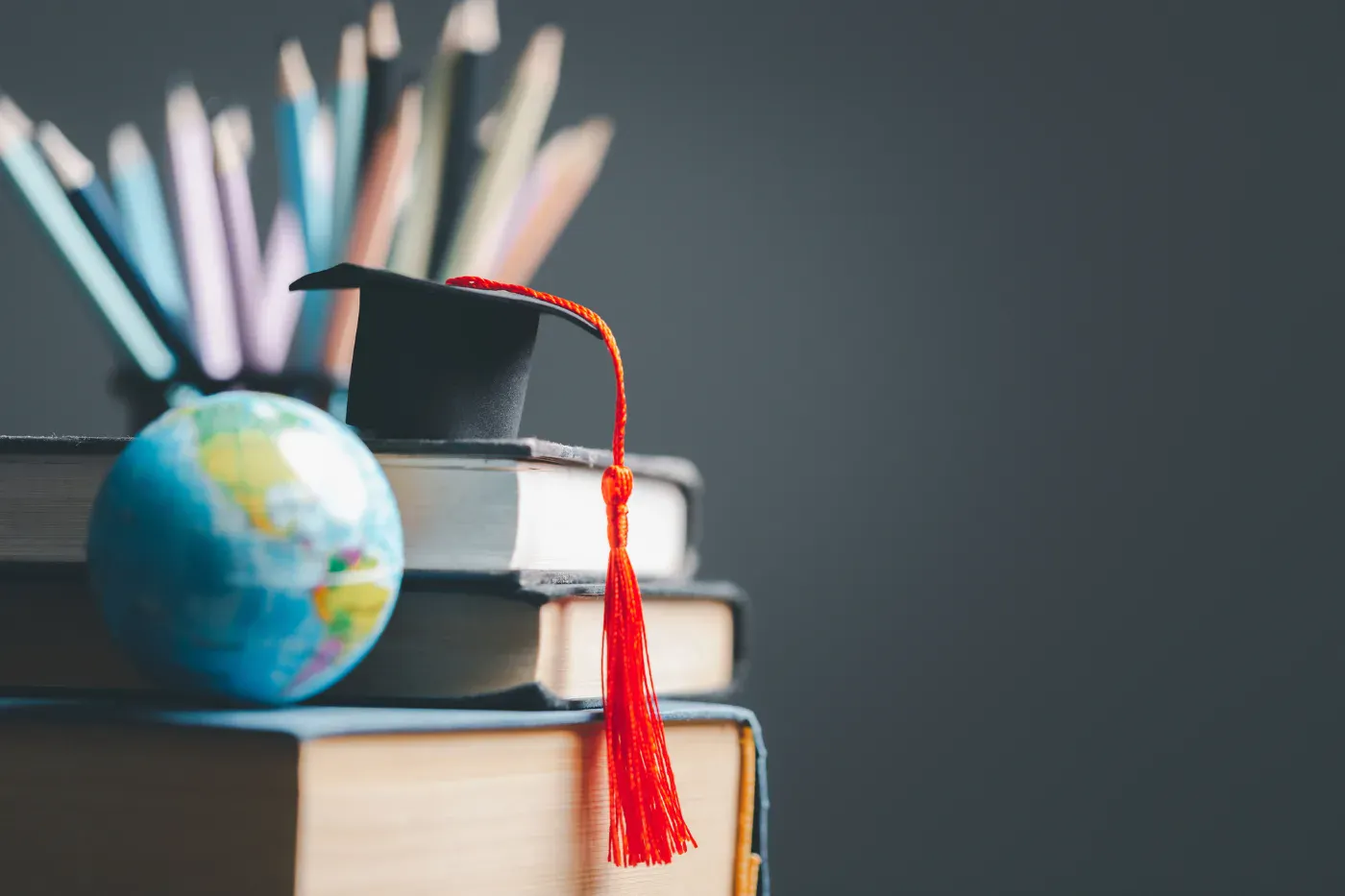 Graduation cap on books beside a globe
