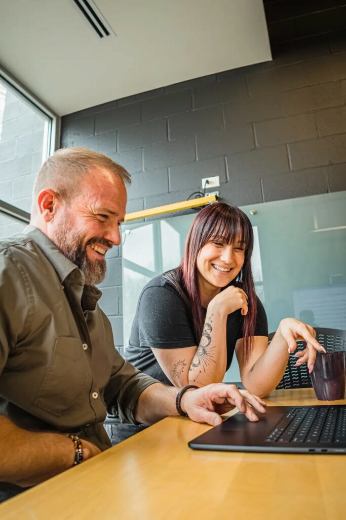 Two Brillity teammates laughing over a laptop
